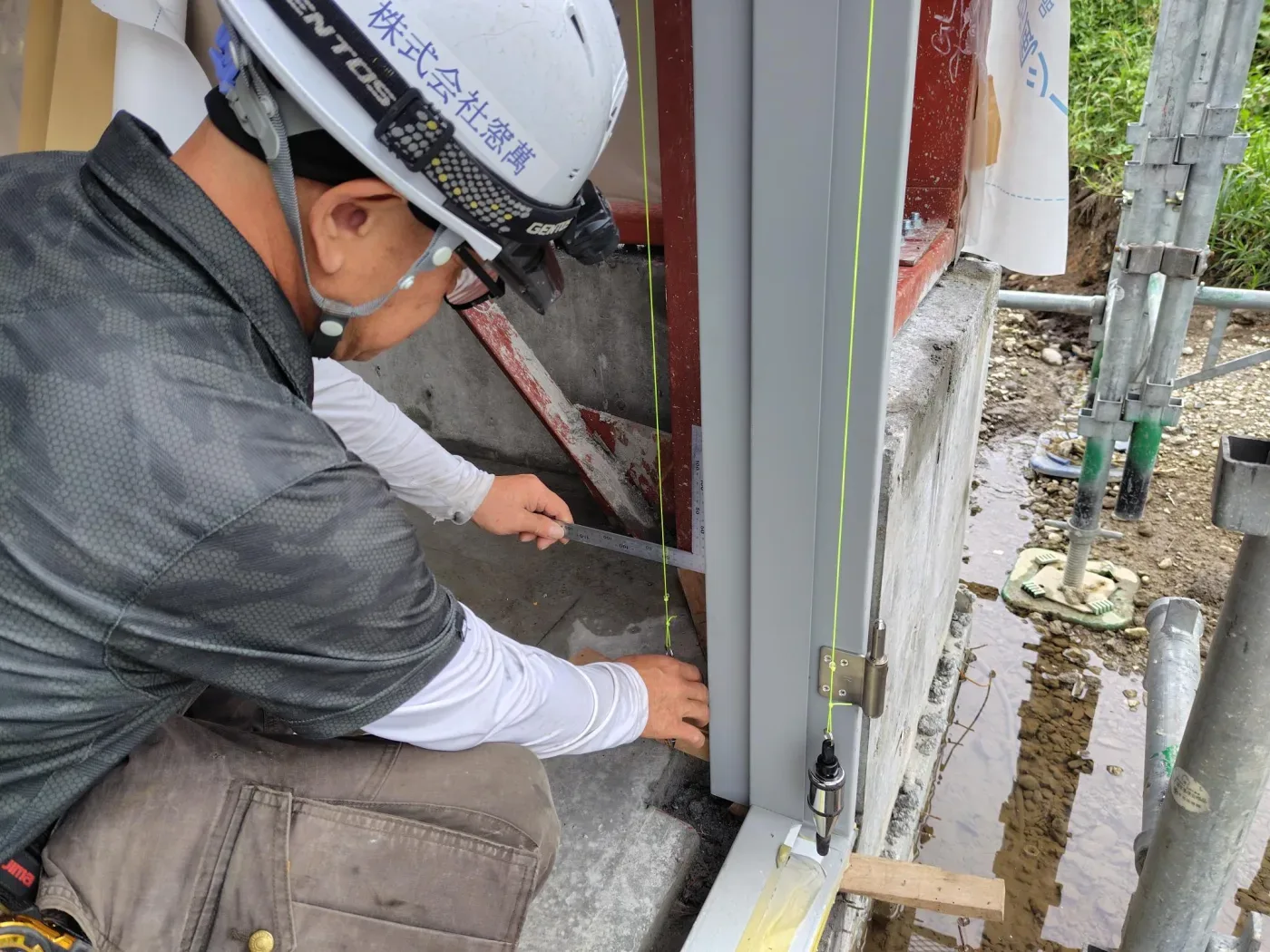 鋼製ドア枠の据付・下げ振りで垂直を確認する職人